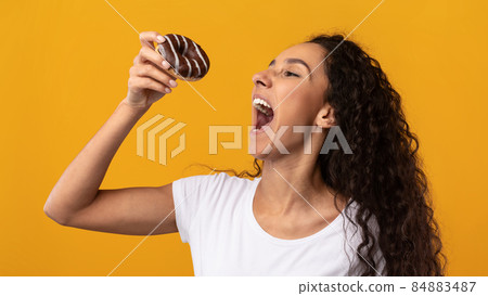 Happy Latin Lady Holding Doughnut Biting Cake At Studio Happy Latin Lady Holding Doughnut Biting Cake At Studio 84883487