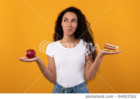 Portrait of Smiling Latin Lady Holding Apple And Burger 84883562