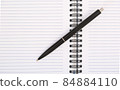 Black pen on top of white notebook 84884110