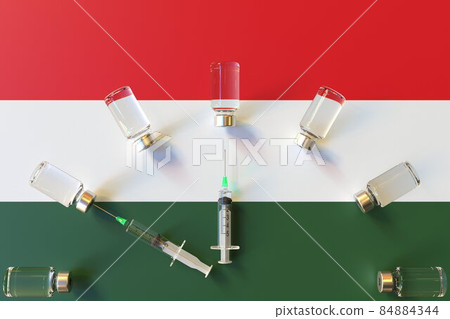 Glass vials and syringes on the flag of Hungary. Vaccination related conceptual 3D rendering Glass vials and syringes on the flag of Hungary. Vaccination related conceptual 3D rendering 84884344