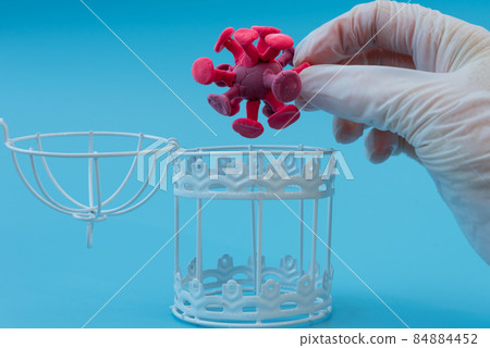 A gloved hand takes the coronavirus out of a metal prison. The concept of biological weapons development. Danger to humanity 84884452