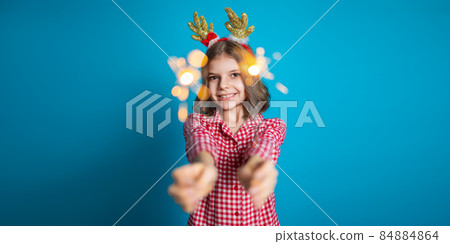 Happy small girl looking with admiration at burning sparkler in her hand over blue background Happy small girl looking with admiration at burning sparkler in her hand over blue background 84884864