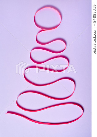 Christmas tree made of pink ribbon on purple paper background 84885319