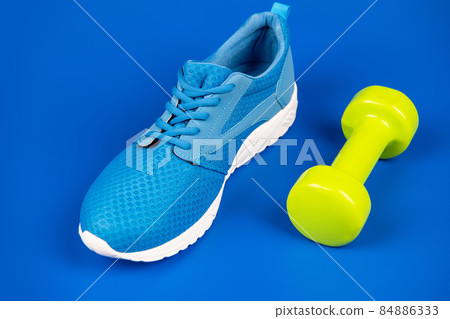 footwear for training with dumbbell on blue background, sport accessory 84886333