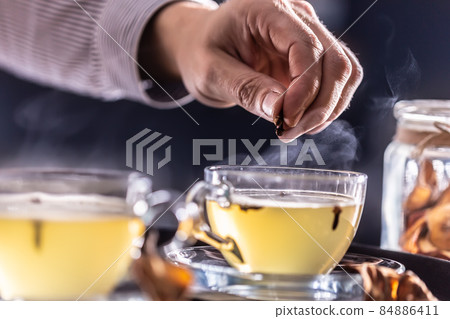 Detail of a bartender's hand flavoring hot mulled wine with cloves 84886411