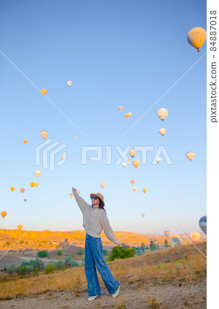 Happy woman during sunrise watching hot air balloons in Cappadocia, Turkey 84887018