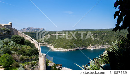 Blue and turquoise Mediterranean sea under the ramparts of the medieval citadel of Bonifacio 84887589