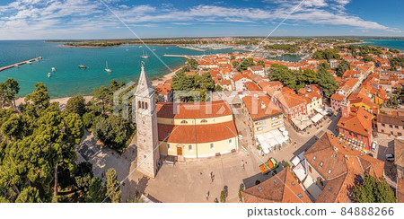 Drone panorama over the roofs of the Croatian coastal town of Novigrad with harbor and church during daytime 84888266