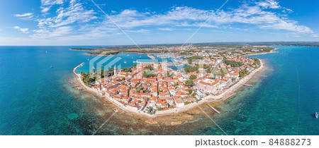 Drone panorama over the Croatian coastal town Novigrad with harbor and promenade taken from the sea side during the day 84888273