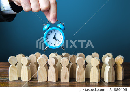 A businessman is holding an alarm clock over a crowd of people. Time management. Hourly wages, strict work limits and time allotted for rest. Urgently, speeding up, deadline. Test, trial period 84889406
