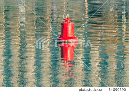 Floating red navigational buoy on water surface. 84890890