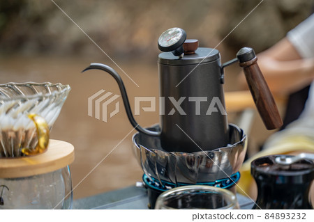 Man dripping hot coffee and camping near river at nature park. Outdoor activity and relax on holiday. Man dripping hot coffee and camping near river at nature park. Outdoor activity and relax on holiday. 84893232