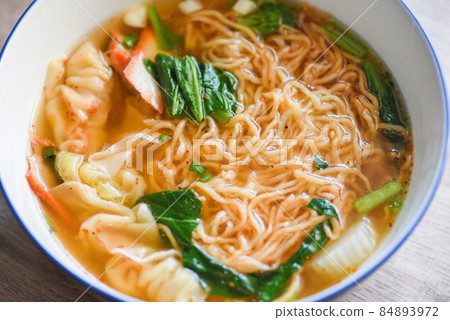 soup noodle wonton pork yellow noodle with red roasted pork dumpling and bog choy chinese vegetable in soup bowl on wooden table, top view 84893972