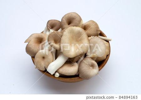 Fresh oyster mushroom in wooden bowl in bowl on white background. Fresh oyster mushroom in wooden bowl in bowl on white background. 84894163