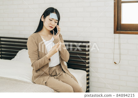 Asian woman who has a fever and calls online medical treatment on her smartphone 84894215