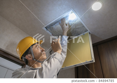 Image of a worker inspecting the ceiling from the ceiling inspection port 84894785