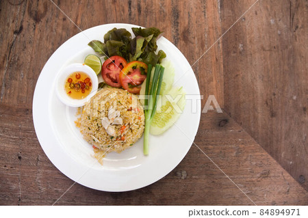 Fried rice with crab, tomato, cucumber, spring onion, and fish sauce on wood table 84894971
