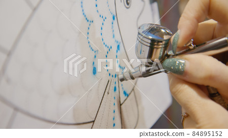 Woman artist learns to paint with airbrush with acrylic dye, paper and easel. Concept modern art, airbrushing, aerography, graffiti, aerosol spray 84895152