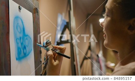 Woman artist learns to paint with airbrush with acrylic dye, paper and easel. Concept modern art, airbrushing, aerography, graffiti, aerosol spray Woman artist learns to paint with airbrush with acrylic dye, paper and easel. Concept modern art, airbrushing, aerography, graffiti, aerosol spray 84895157