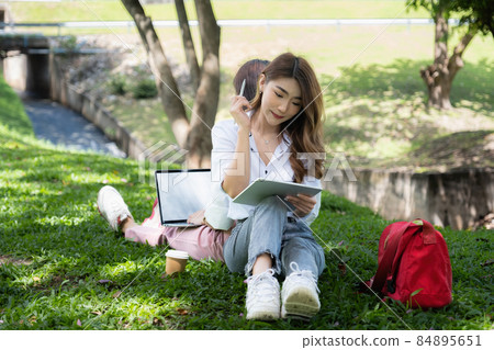 Two students are sitting in university during reading a book and communication. Study, education, university, college, graduate concept. 84895651