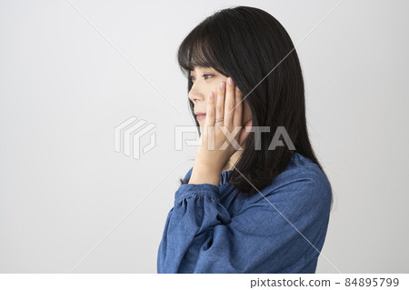 一個年輕女子戴著結婚戒指，把手放在臉頰上 84895799