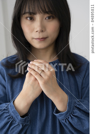 A young woman wearing a wedding ring on her left ring finger 84895811