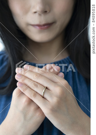 A young woman wearing a wedding ring on her left ring finger 84895818