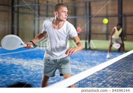 Concentrated paddle tennis player preparing to hit forehand Concentrated paddle tennis player preparing to hit forehand 84896144