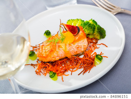 Steak of fried salmon with smoked carrots, broccoli, cucumbers and fig on plate 84896151