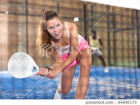 Expressive girl hitting two handed backhand during paddle tennis match 84896170