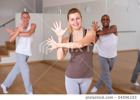 Cheerful woman practicing vigorous movements in group dance class Cheerful woman practicing vigorous movements in group dance class 84896183