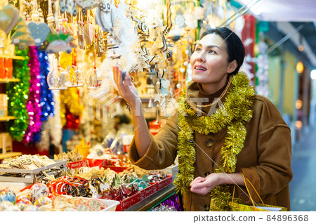 Asian female choosing decorations at Christmas fair Asian female choosing decorations at Christmas fair 84896368