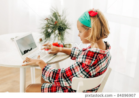 A teenage girl wishes Merry Christmas and New Year on a laptop. Congratulations Online A teenage girl wishes Merry Christmas and New Year on a laptop. Congratulations Online 84896907