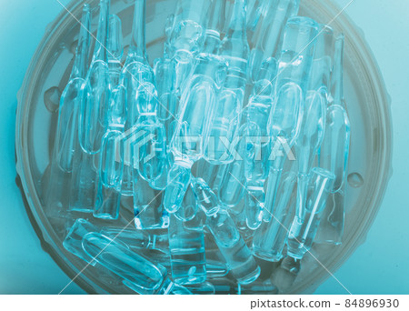 Glass medical ampoule vial for injection. Medicine is liquid sodium chloride with of aqueous solution in ampulla. Close up. Bottles ampule multicolor. 84896930