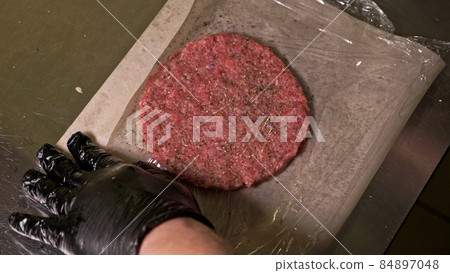 Cook makes meat medallions for burgers. Chef in black food gloves makes cutlet. Cutlets are leveled in steel ring in an even medallion. Cook makes meat medallions for burgers. Chef in black food gloves makes cutlet. Cutlets are leveled in steel ring in an even medallion. 84897048