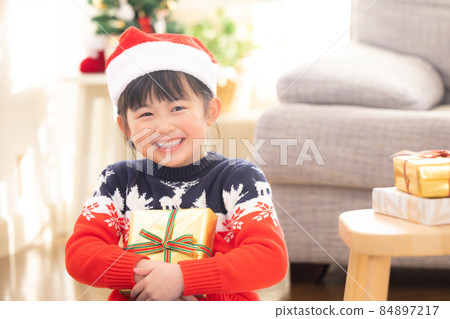 A girl who smiles when she receives a Christmas present A girl who smiles when she receives a Christmas present 84897217