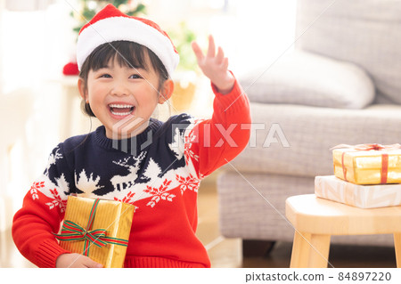 A girl who smiles when she receives a Christmas present A girl who smiles when she receives a Christmas present 84897220