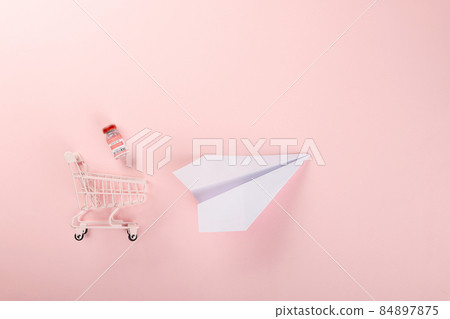 Shopping cart with vaccine vials bottles and syringes for vaccination against coronavirus and paper plane Shopping cart with vaccine vials bottles and syringes for vaccination against coronavirus and paper plane 84897875