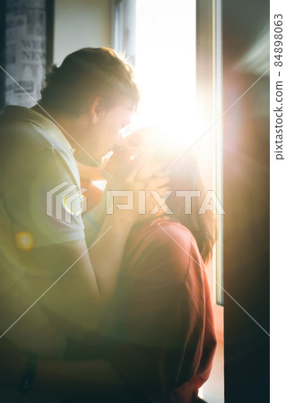 Portrait of a couple kissing against the backdrop of the sunset illuminating the camera. Front view. Portrait of a couple kissing against the backdrop of the sunset illuminating the camera. Front view. 84898063