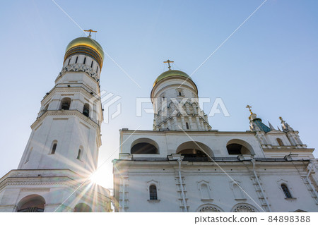 Ivan the Great Bell Tower, with Assumption Belfry on the right in Moscow Kremlin. Blue sky background with sunbeams 84898388