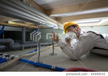 一個穿著工作服的男人在檢查房子的地板 84899242