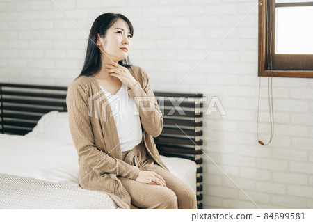 Japanese woman suffering from throat, tonsils and neck in bedroom 84899581