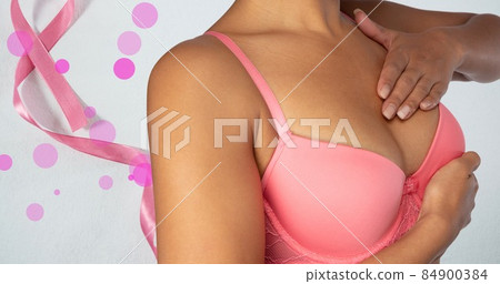 Midsection of woman in pink bra with breast cancer ribbon, copy space 84900384