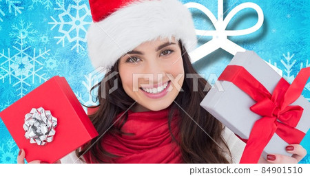 Portrait of happy young woman in santa hat with christmas presents over blue background, copy space 84901510