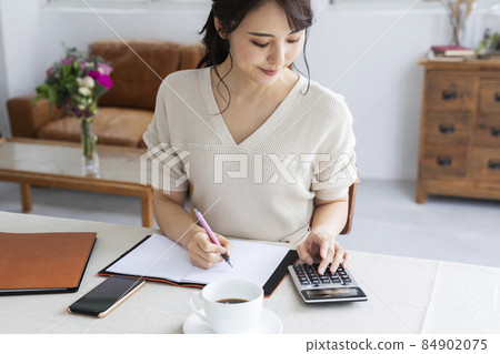 使用計算器計算的年輕女子 84902075