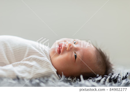 Side view happy newborn baby lying on a carpet looking at camera and smile comfortable and safety.Happiness Cute Asian newborn sleeping and napping on carpet.Newborn Baby photography concept 84902277