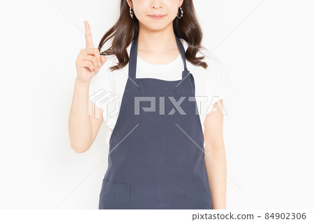 Young girl in an apron standing in front of a white background and showing points 84902306