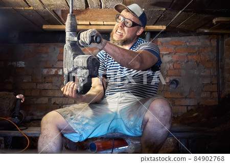 Funny bearded man with heavy duty perforator in the basement of the house Funny bearded man with heavy duty perforator in the basement of the house 84902768