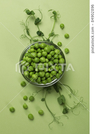 Bowl with pea seeds on green background 84902896