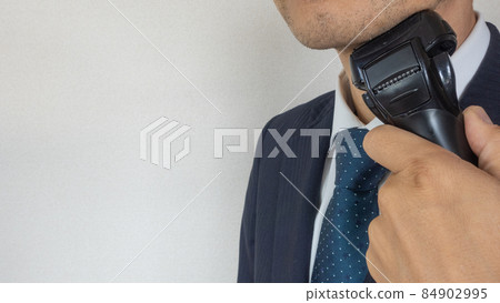 一個商人用電動剃須刀刮鬍子 84902995